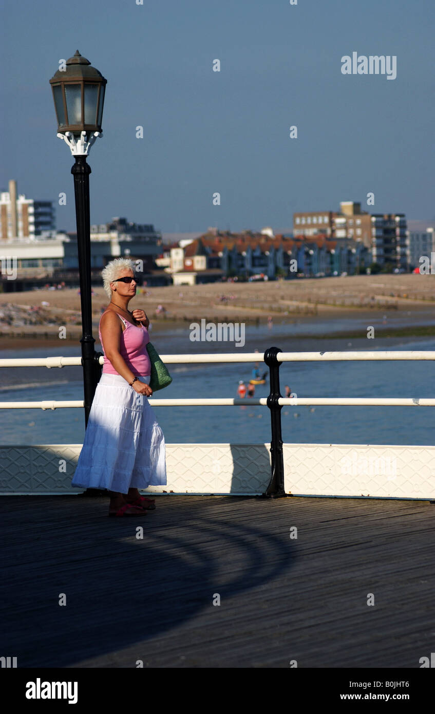 Una donna si erge su Worthing Pier, Inghilterra su una calda giornata di sole. Foto Stock