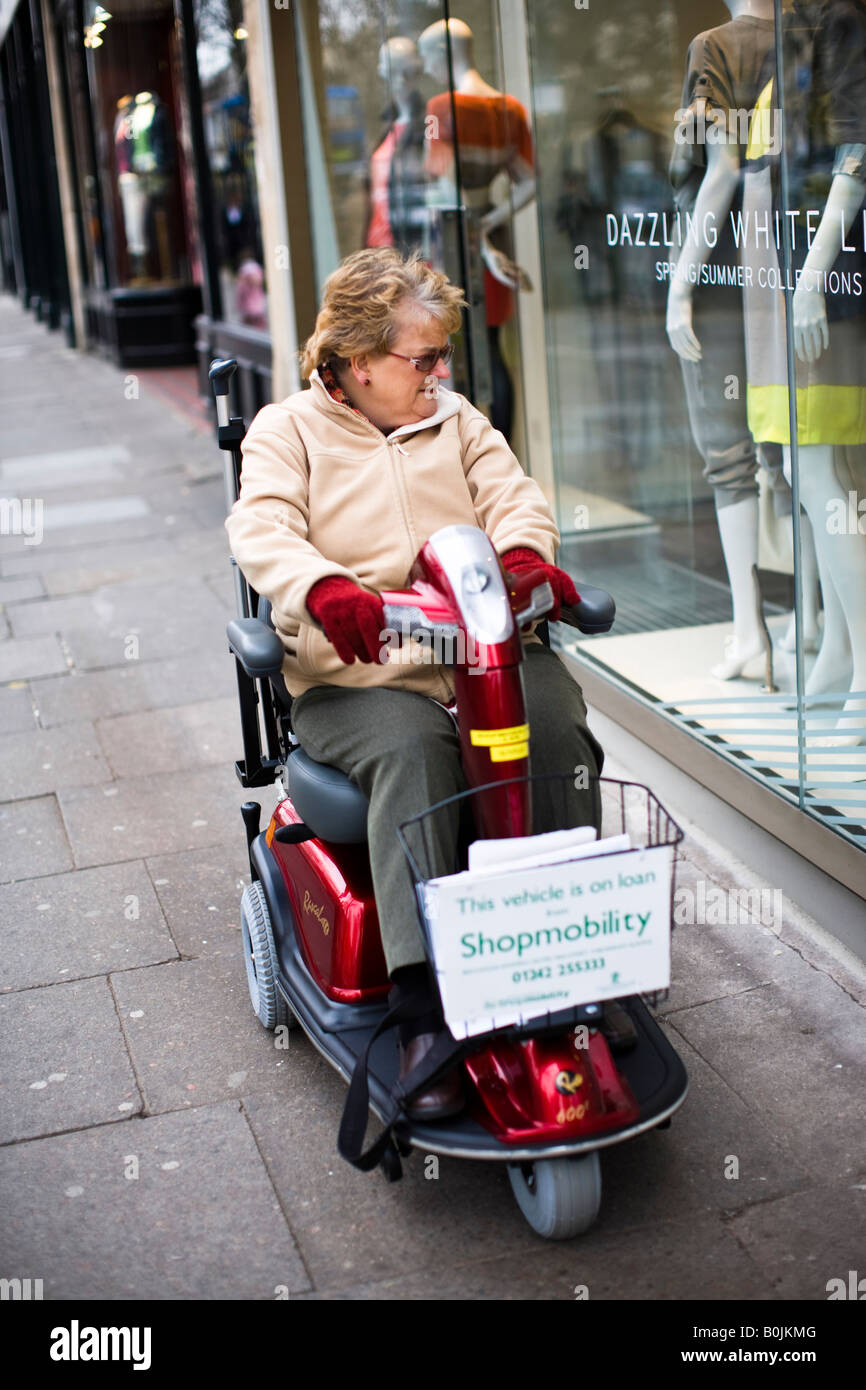 Titolare di pensione o di rendita su uno scooter Shopmobility in Cheltenham town center Foto Stock