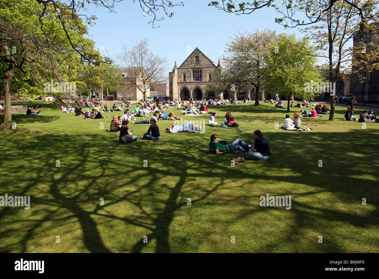 Gli studenti di lettura, parlando e bagni di sole sul prato fuori Elphinstone Hall dell'Università di Aberdeen, Scozia, Regno Unito Foto Stock