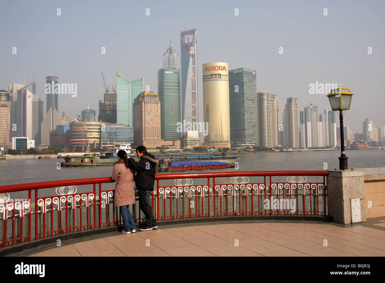 Coppia cinese guardando attraverso il fiume Huangpu verso la skyline di Pudong, Shanghai, Foto Stock