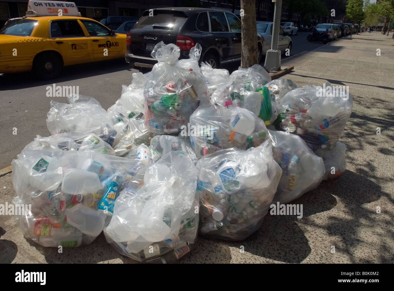 Bicchiere di plastica e contenitori di metallo confezionato in una busta di plastica trasparente attendono il prelevamento dal marciapiede Foto Stock