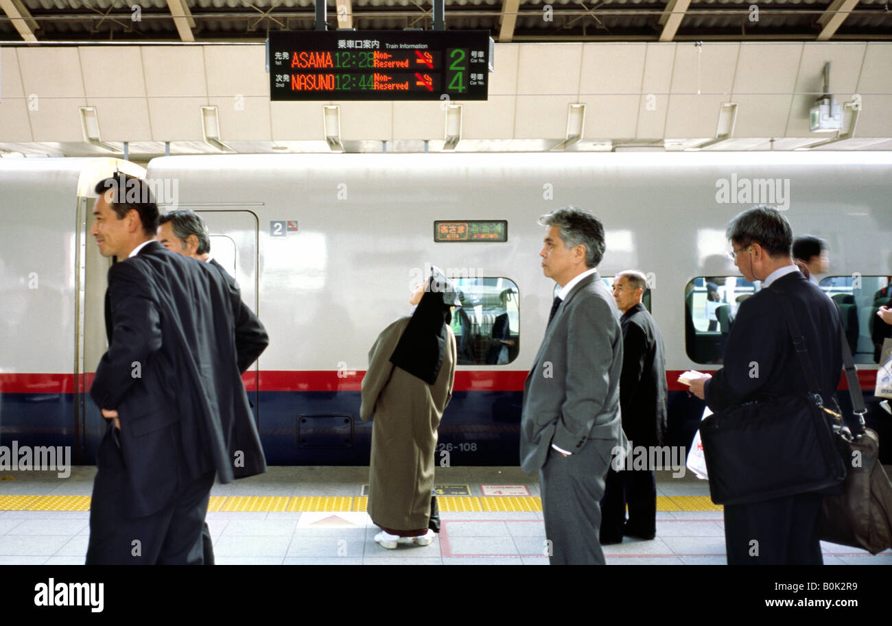 Nun controllo inscriber per l'orario di partenza di un treno Shinkansen su una piattaforma alla stazione di Tokyo in Giappone. Foto Stock