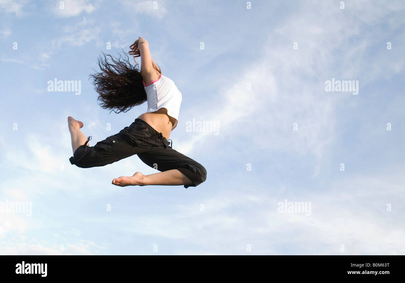 Una giovane donna volare alto su un trampolino verso il cielo, REGNO UNITO Foto Stock