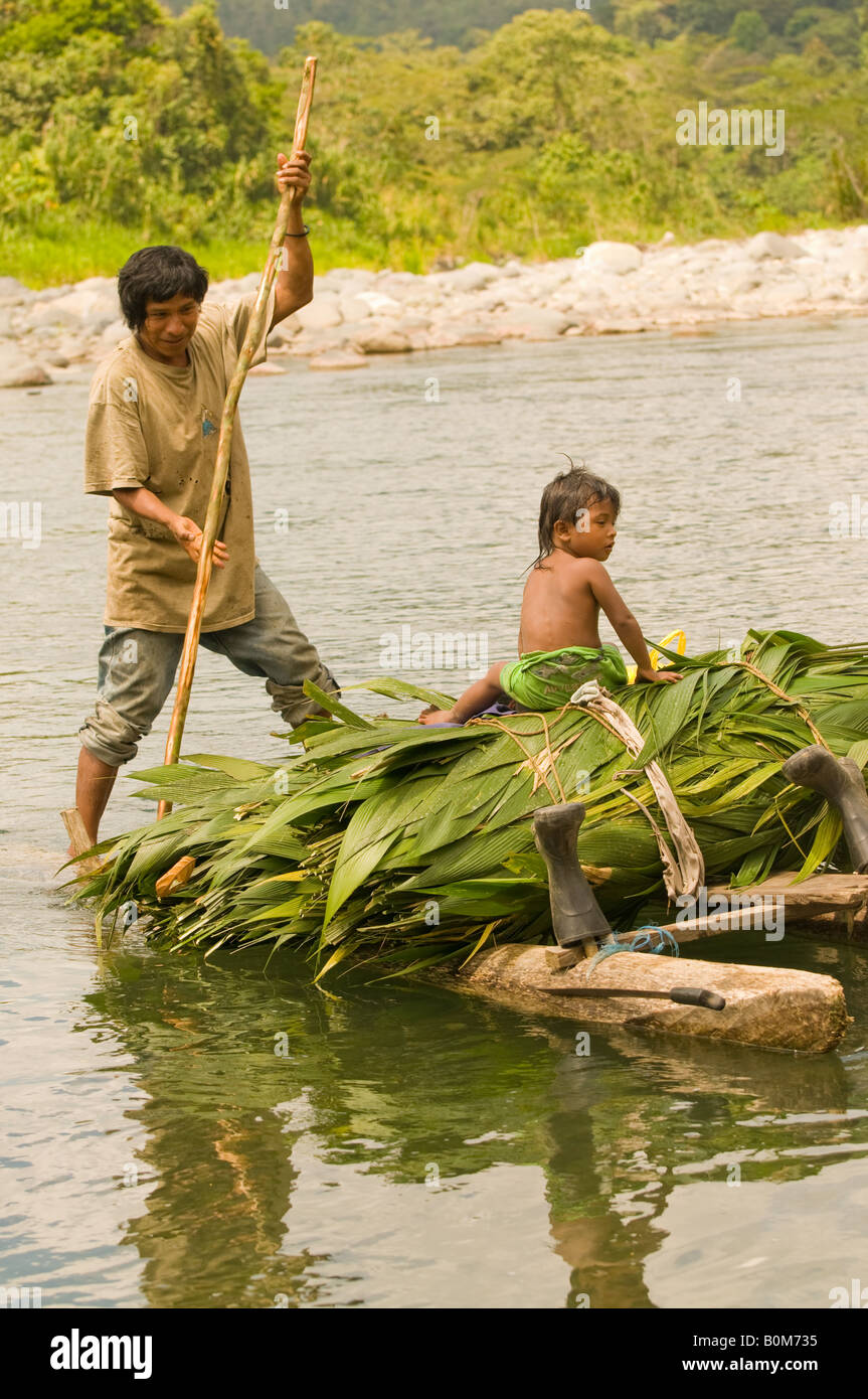 COSTA RICA Cabecar indigene tribù indiana padre e figlio attraversando la parte inferiore del fiume Pacuare su una zattera di registro trasporto Suyta Palm Foto Stock