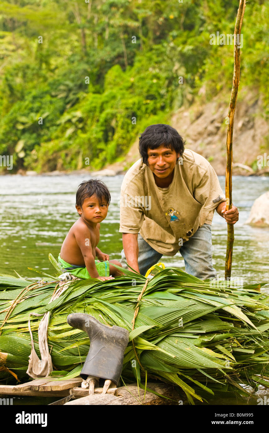 COSTA RICA indigene tribù Cabecar padre e figlio attraversando la parte inferiore del fiume Pacuare su una zattera di registro trasporto Suyta Palm. Foto Stock