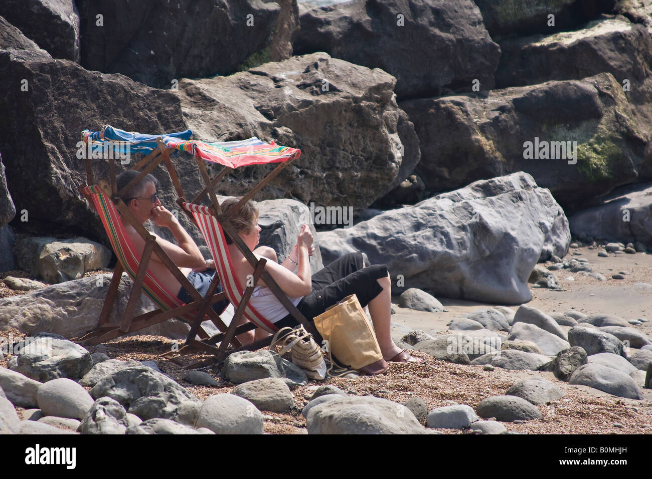 Coppia matura prendere il sole sulla spiaggia a Steephill Cove, Isola di Wight, Inghilterra, Regno Unito Foto Stock