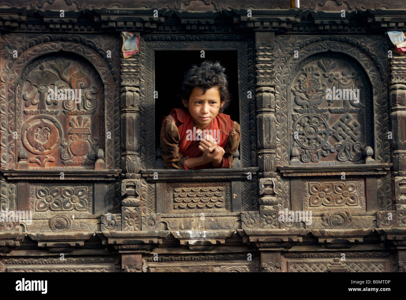 Una ragazza si affaccia alla finestra del suo splendidamente scolpito house, Gatlang, Tamang Heritage Trail, Nepal Foto Stock
