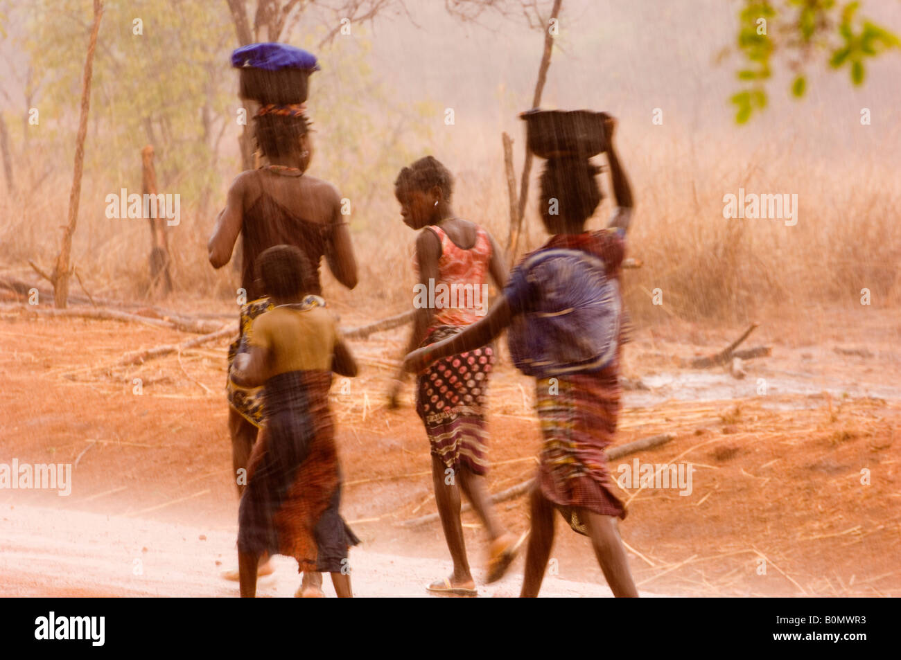 I bambini a piedi sotto la pioggia battente vicino Mboko Camp in Reserva do Niassa, Mozambico settentrionale Foto Stock