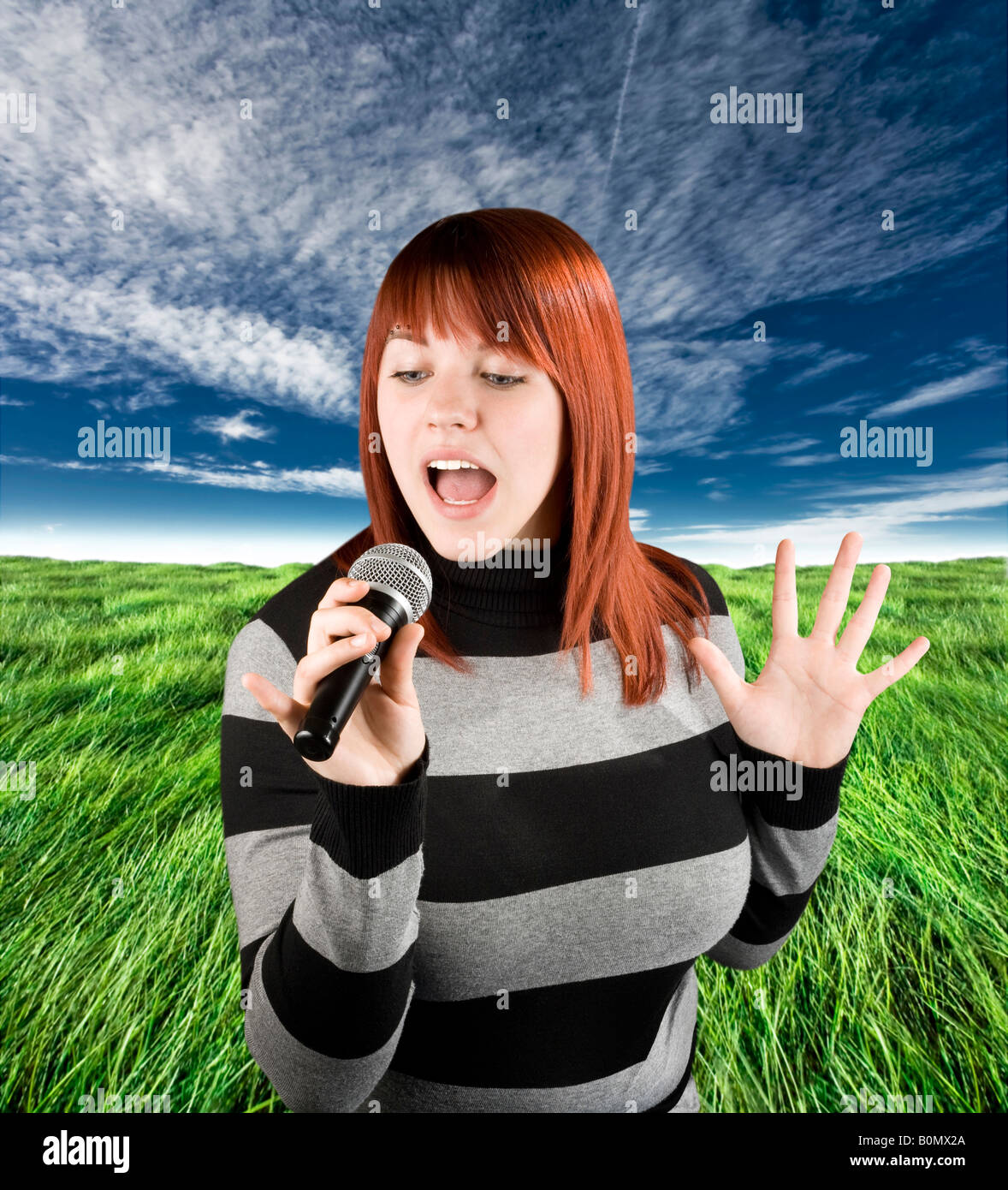 Felice bella ragazza redhead cantando su un microfono karaoke Studio shot Foto Stock