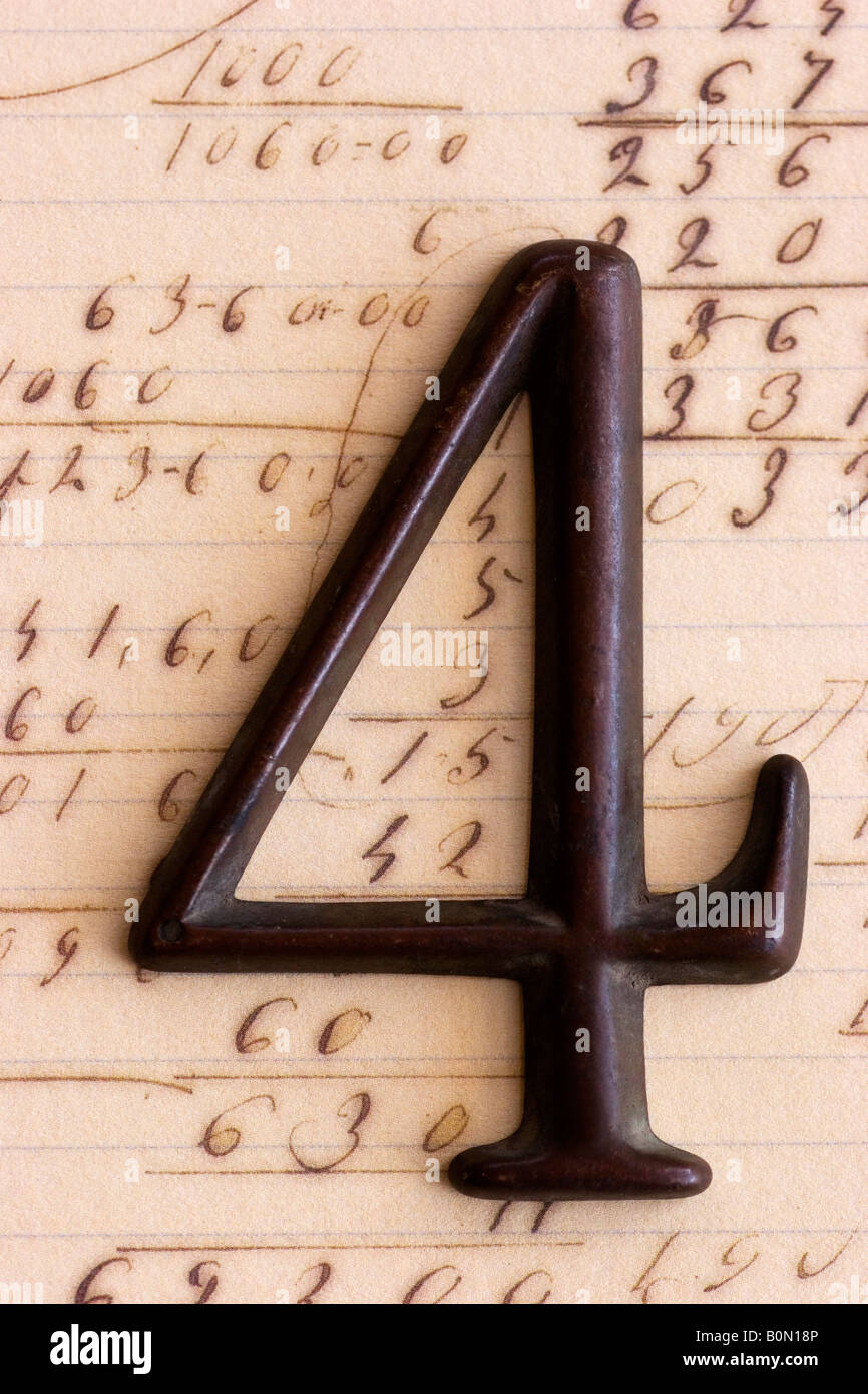 Un metallo scuro sono in numero di quattro nella foto su carta contenente altri numeri e operazioni matematiche. Foto Stock