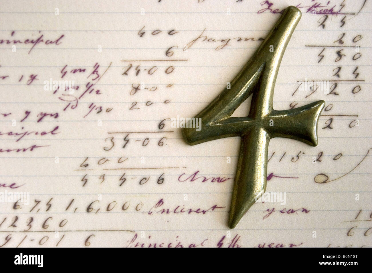 Un ottone numero quattro raffigurato su una carta contenente altri numeri e operazioni matematiche. Foto Stock