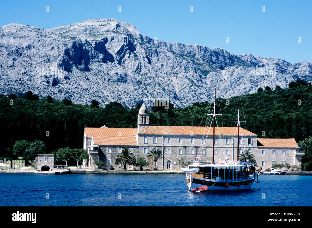 Una barca di crociera solcare le acque al largo della costa della Croazia passa l'isola Adriatica di Badija e il suo monastero del XV secolo Foto Stock