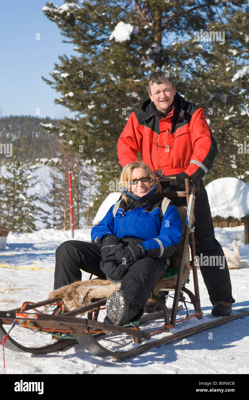 Una donna e un uomo su una slitta durante una corsa in viaggio con i cani da slitta in Lapponia winterly / Svezia settentrionale Foto Stock