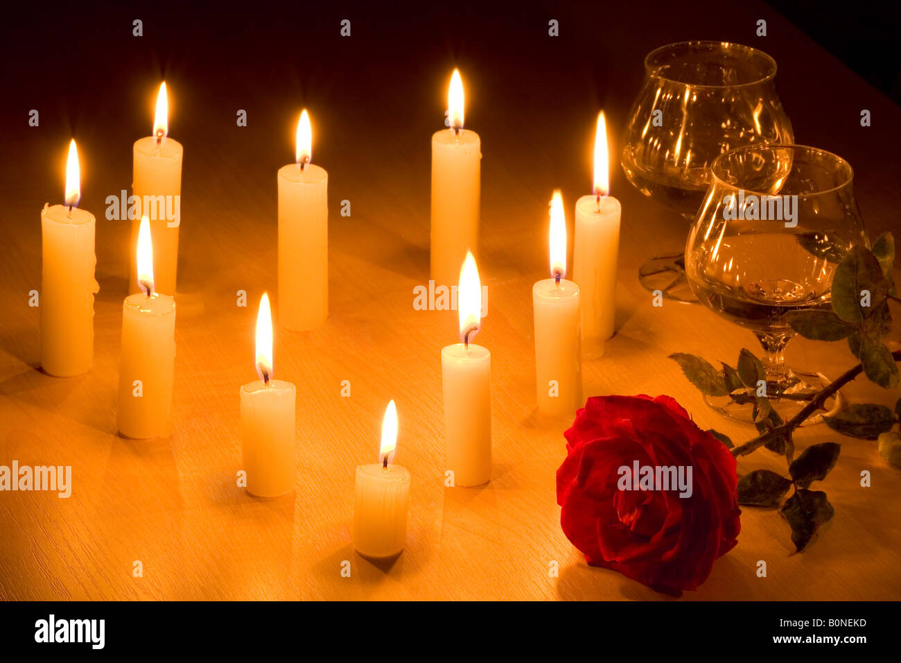 Tabella romantica con il cuore in fiamme di candele due bicchieri di vino rosso e rosa Foto Stock