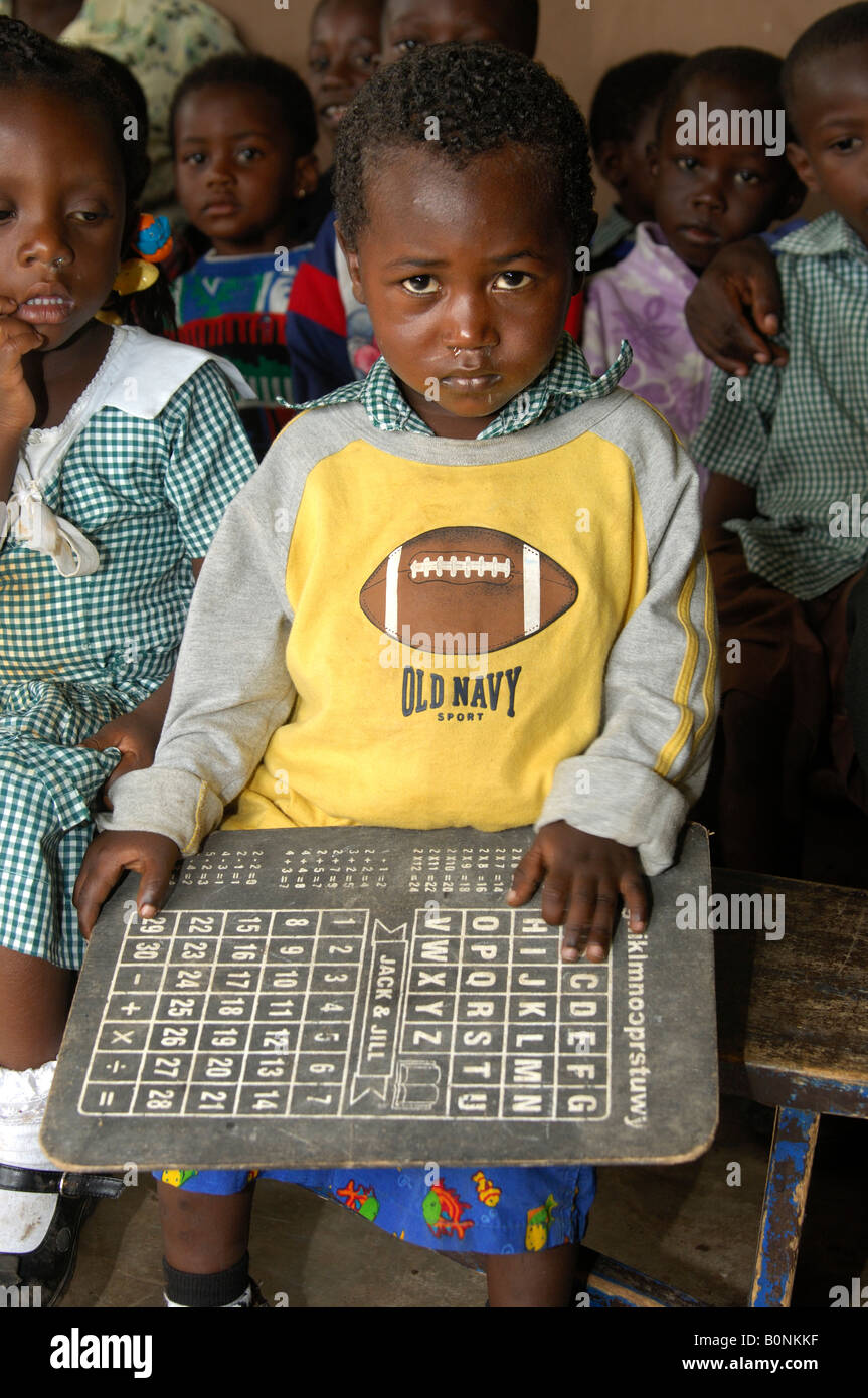 Pre School boy tenendo un alfabeto tabella, centro di cura giornaliera in Akropong Akwapim Regione orientale del Ghana Foto Stock