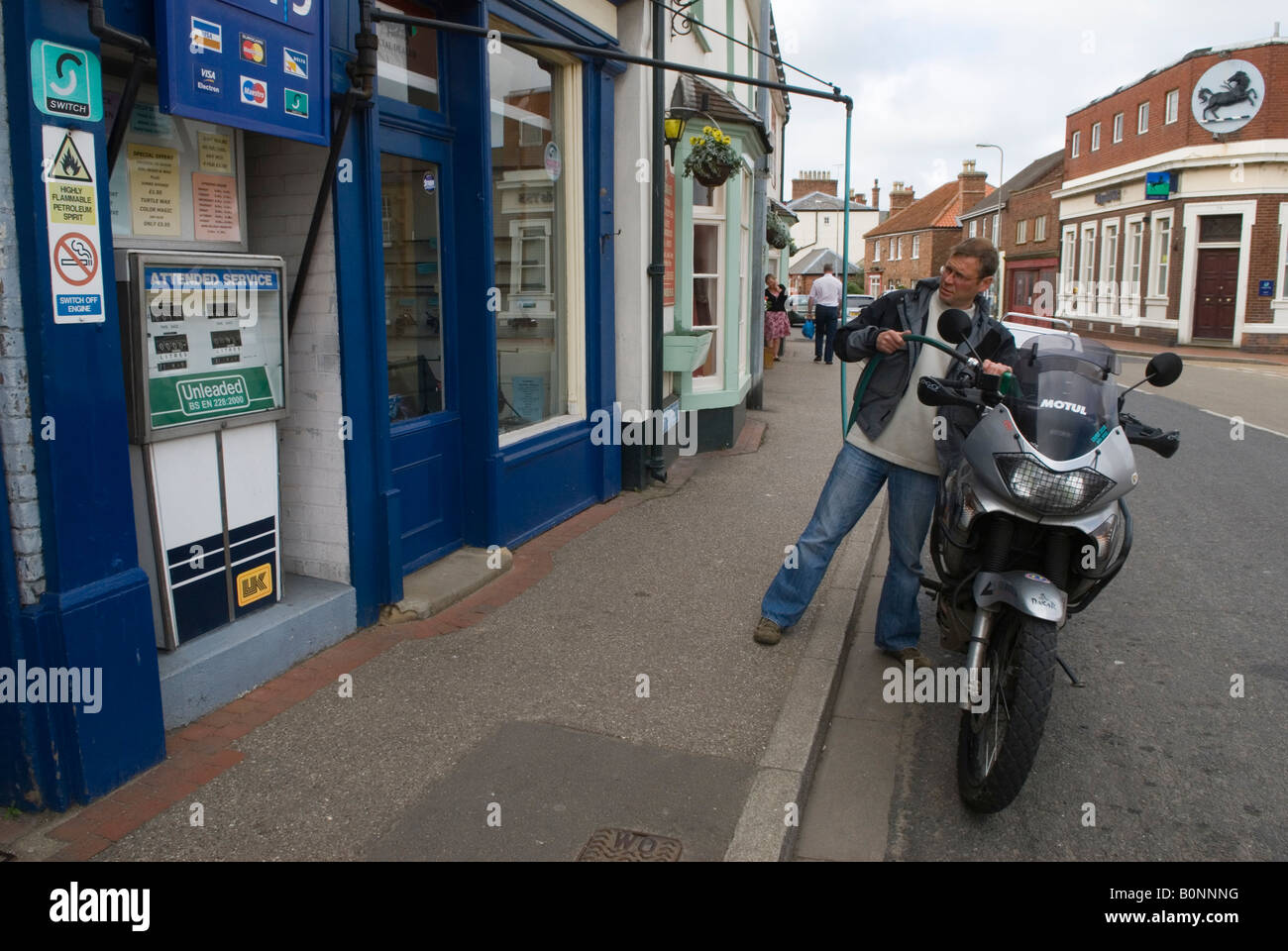 Pompa di benzina retrò UK manichetta sospesa vecchio stile che riempie una motocicletta del cliente. Wainfleet All Saints, Lincolnshire Inghilterra 2000s 2008 Foto Stock