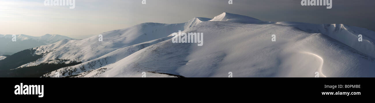 Coperta di neve montagna cresta in primo spuntar del giorno i raggi del sole di illuminazione pastello il giorno e la notte la transizione Foto Stock