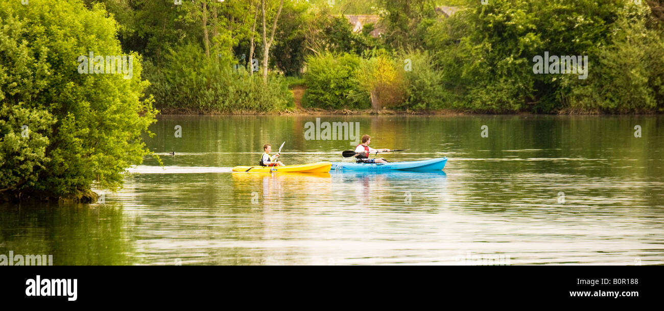 Due canoisti pagaiando su un lago a Cotswold Water Park, Gloucestershire, England, Regno Unito Foto Stock