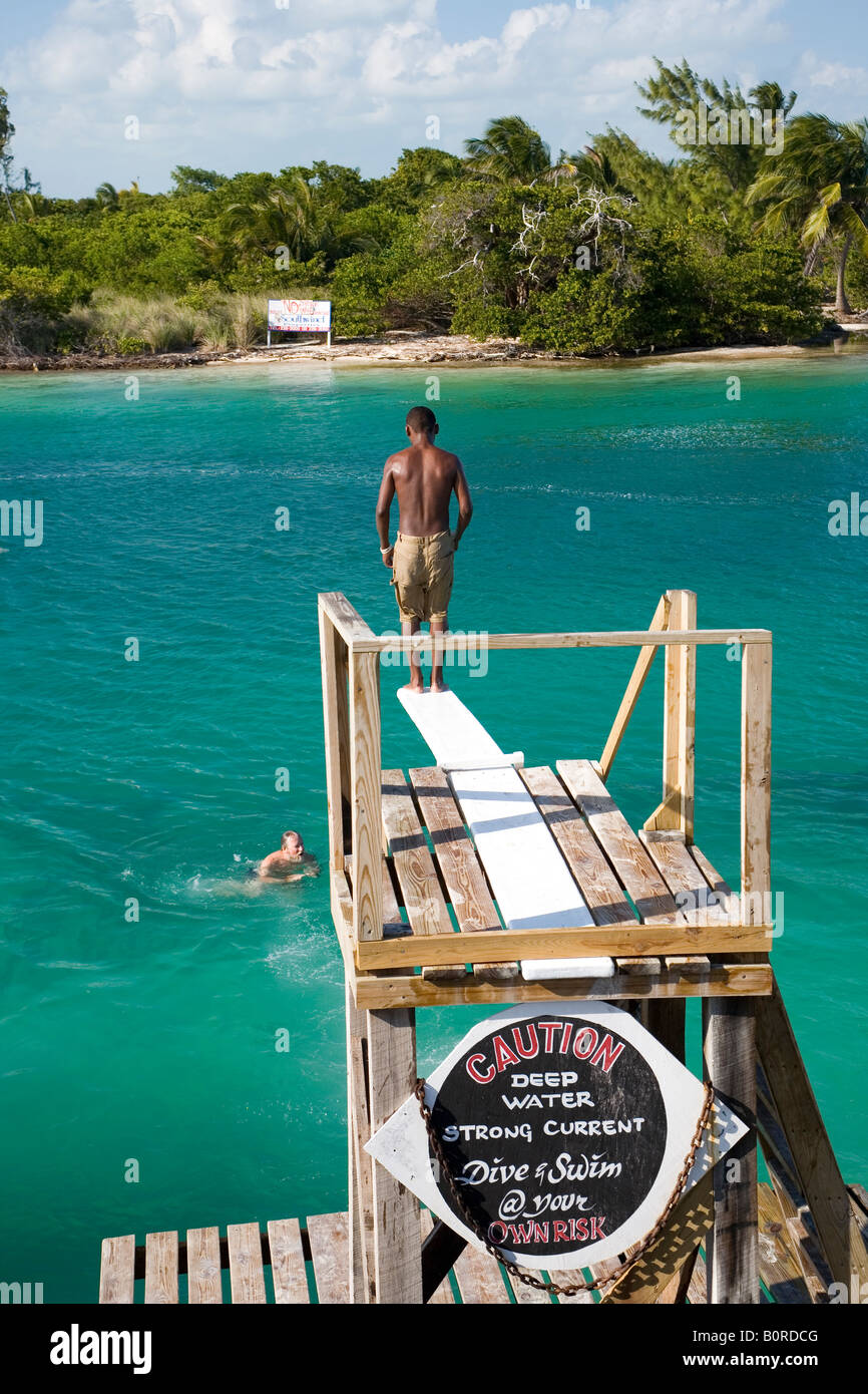 Un uomo è pronto ad immergersi nel limpido mare esotici acqua mentre un segno è avvertenza per la forte corrente Foto Stock