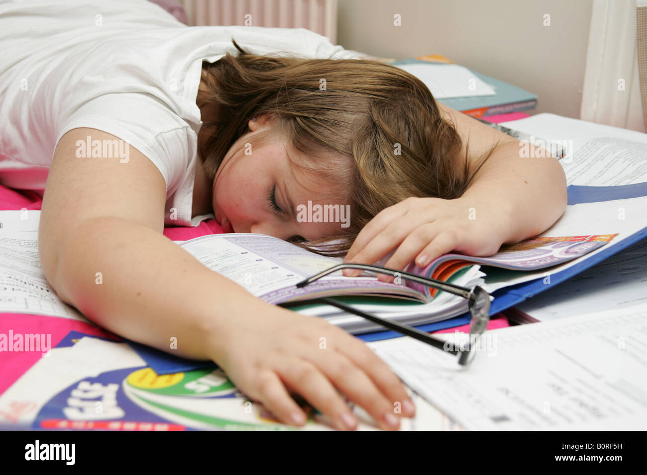 Ragazza adolescente addormentato su una pila di libri scolastici esaurito da rivedere Foto Stock