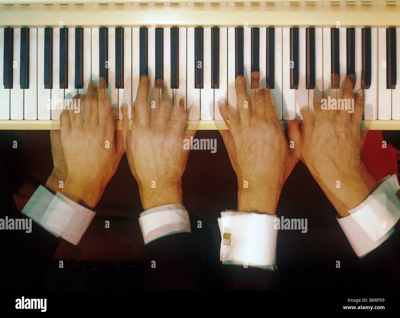 Quattro mani suonando piano Foto stock - Alamy