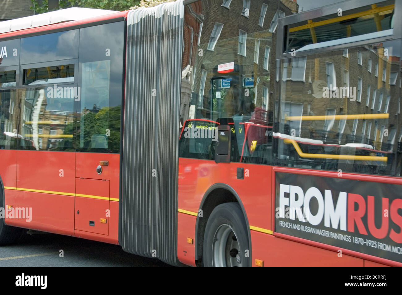 Bendy Bus piegatura con edifici e bus che sopraggiungono riflessa in windows Islington Londra Inghilterra REGNO UNITO Foto Stock