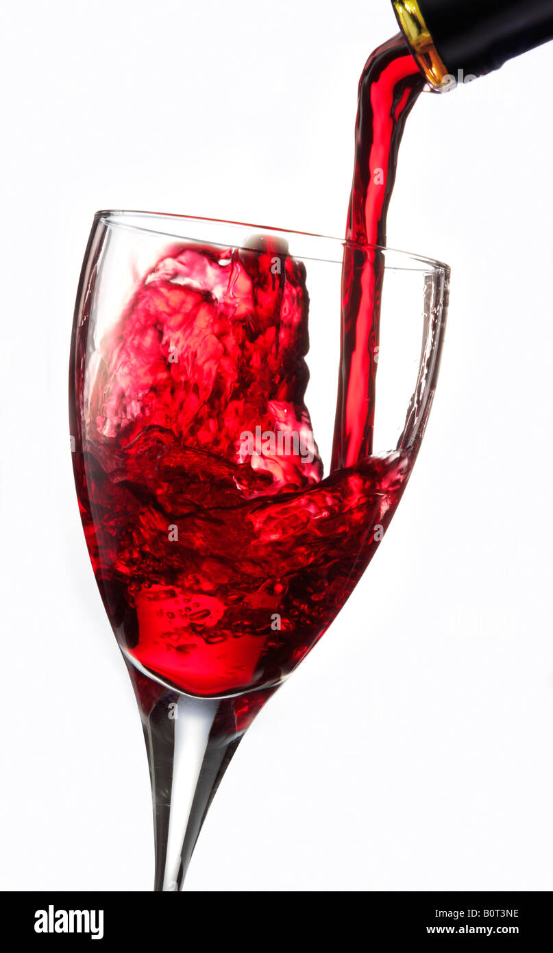 Il vino rosso è versata in un bicchiere contro uno sfondo bianco Foto Stock