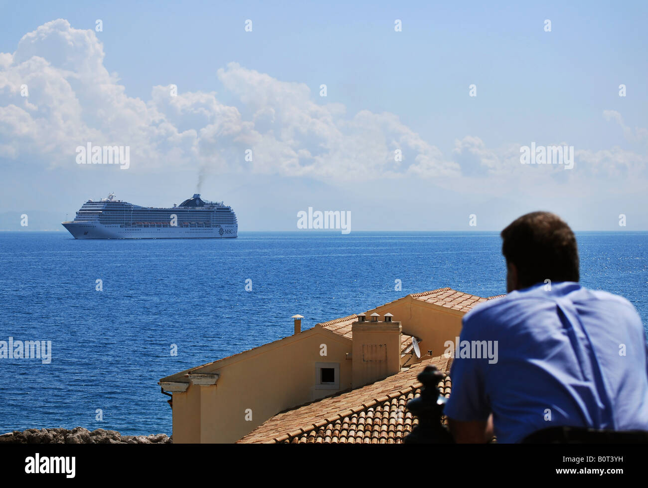 Un uomo la visione di una nave da crociera in arrivo al porto di Corfù, Grecia Foto Stock