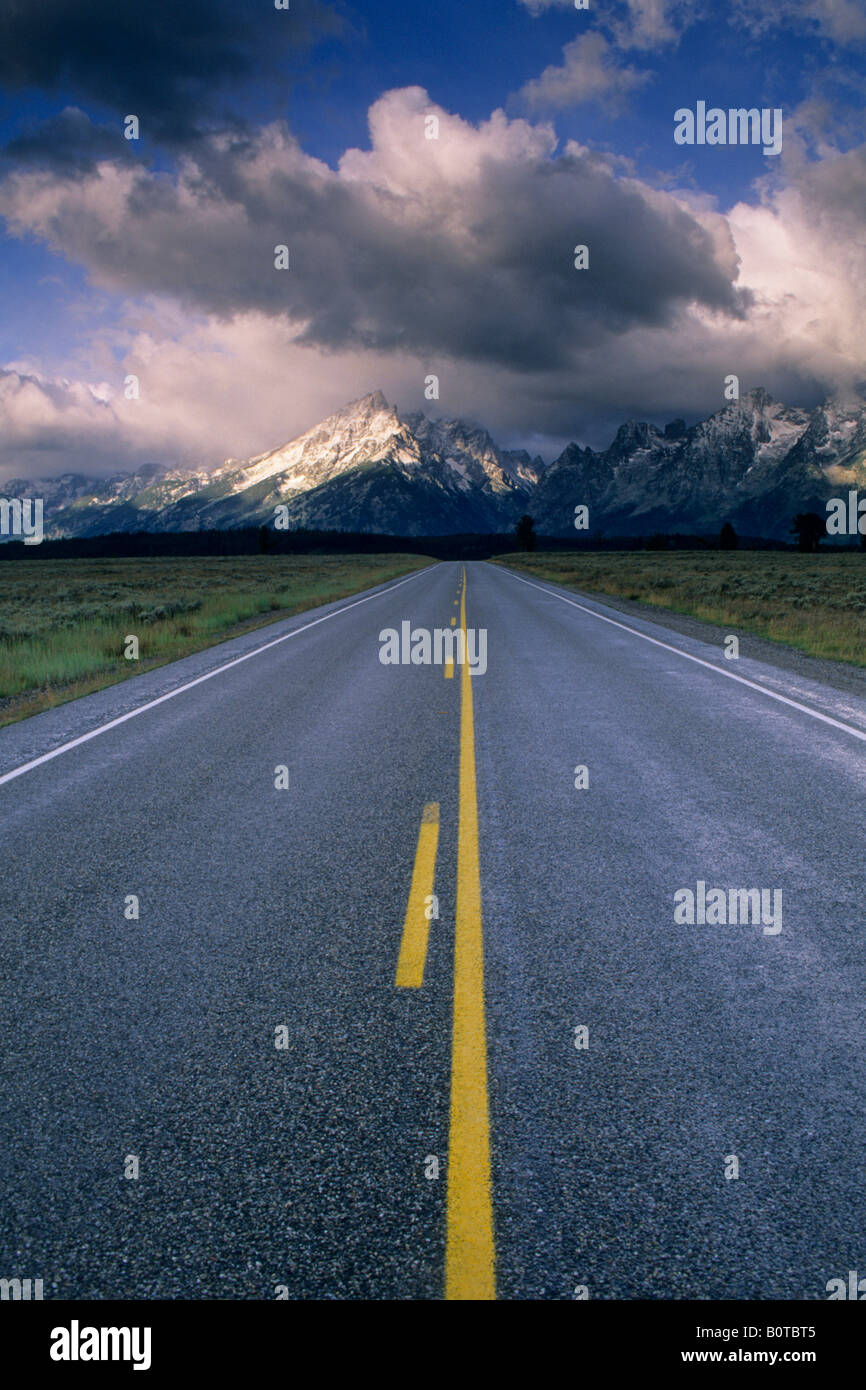 Strada diritta sotto mountain range rispolverato dalla prima neve caduta del Grand Teton National Park Wyoming Foto Stock