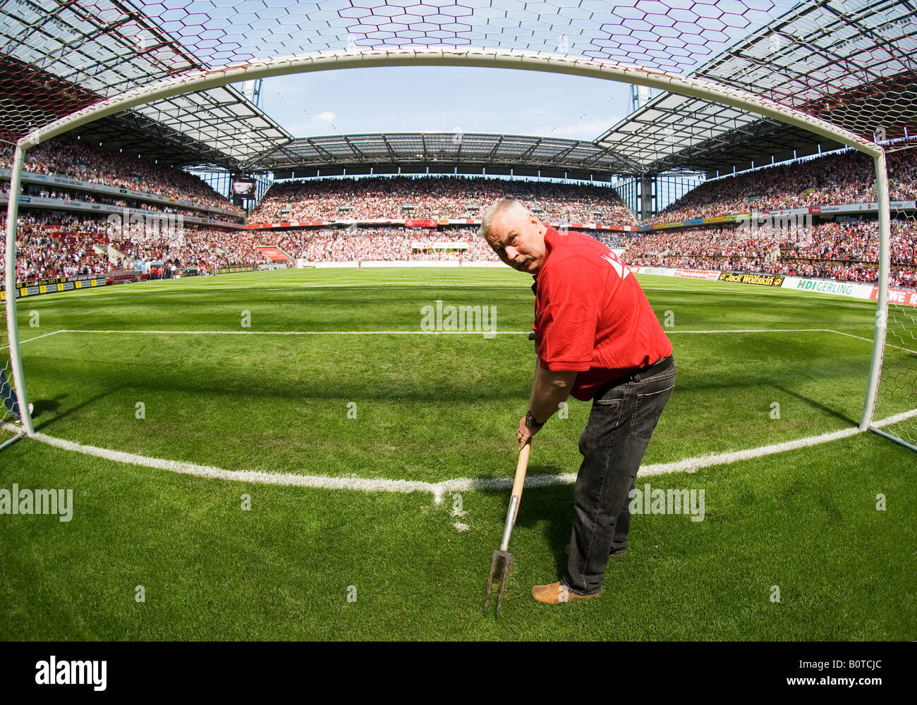 Groundkeeper prepara il passo vuoto interno obiettivo in riempito lo stadio di calcio prima di kick-off Foto Stock
