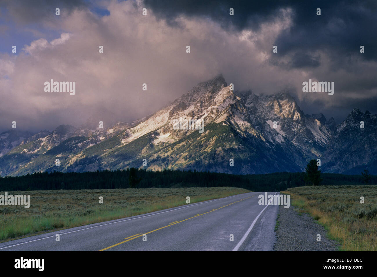 Strada diritta sotto mountain range rispolverato dalla prima neve caduta del Grand Teton National Park Wyoming Foto Stock