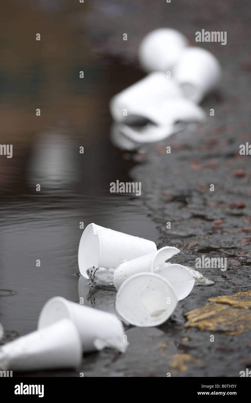 Scartato polistirene STYROFOAM cups giacenti da una pozza in strada Foto Stock