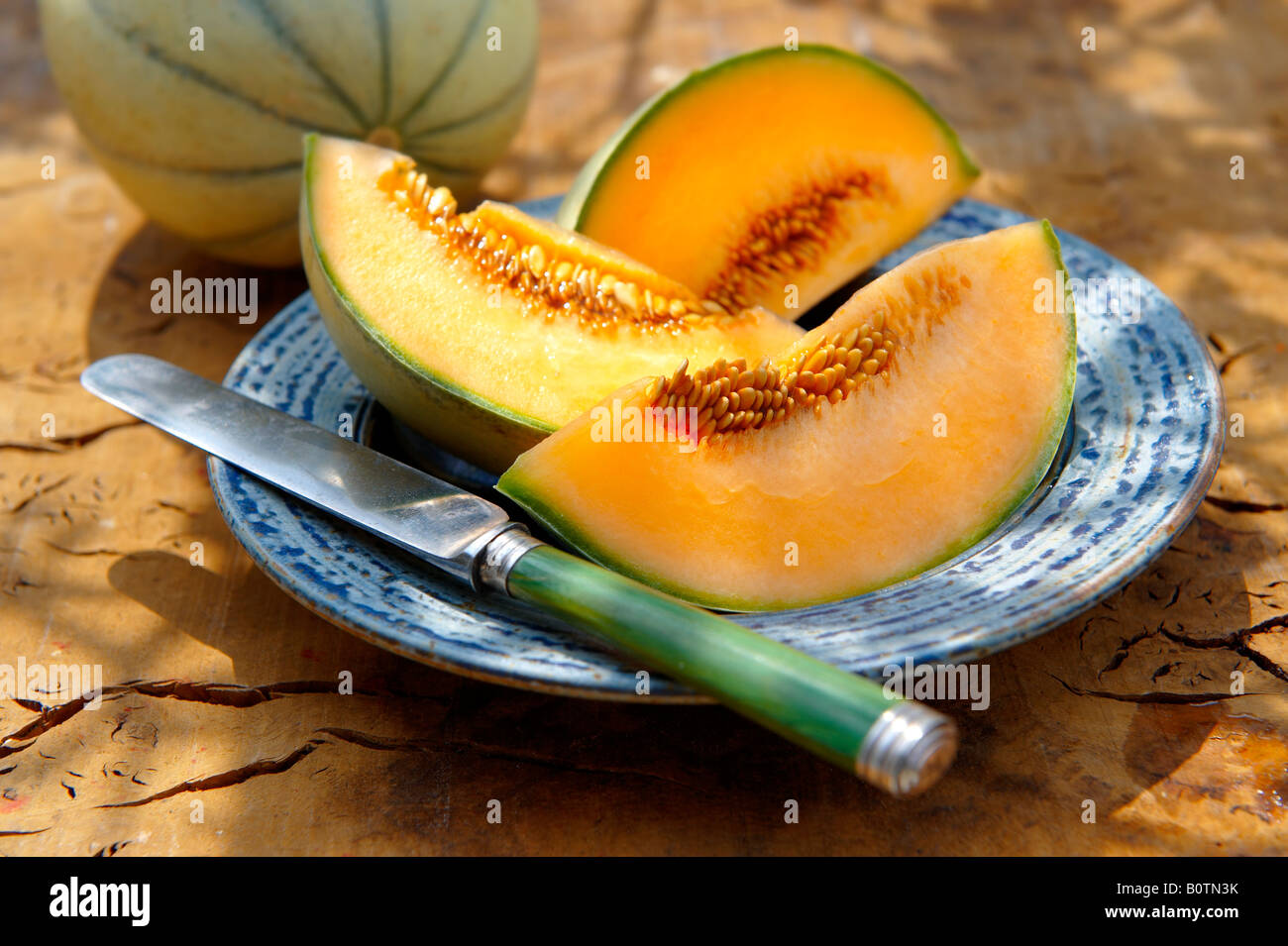 Melone di Cantaloupe appena tagliato su un tavolo in giardino in una giornata di sole Foto Stock
