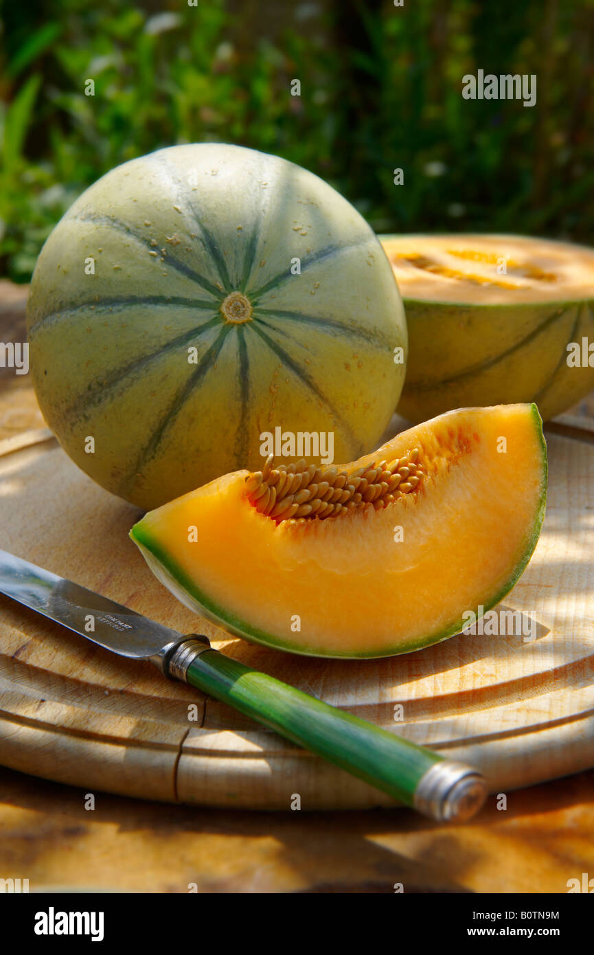 Melone di Cantaloupe tagliato a fresco e tagliato su un legno tavolo in giardino Foto Stock