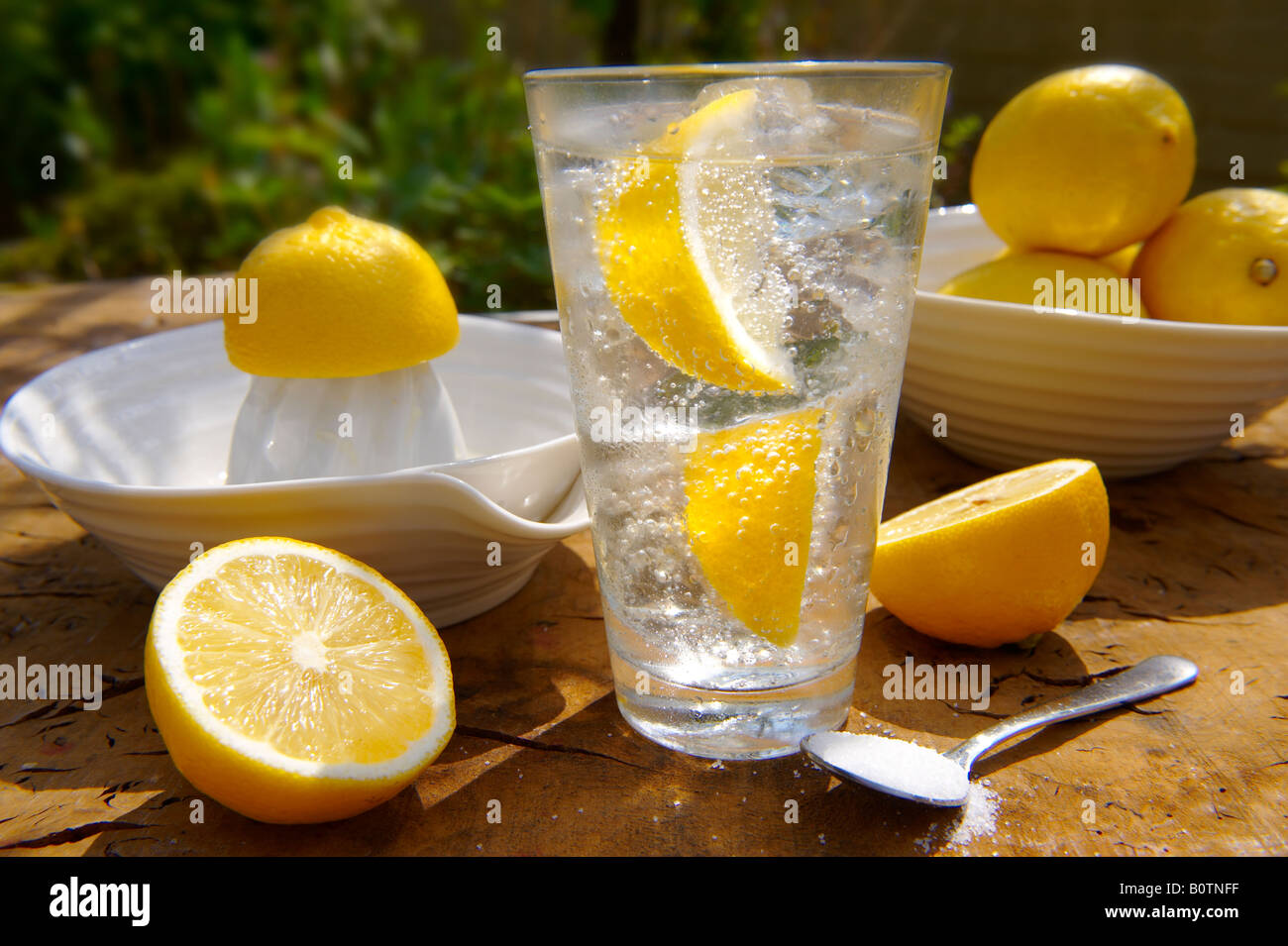 Limonata fatta in casa pronta a bere in una ciotola un tavolo da giardino in legno al sole Foto Stock