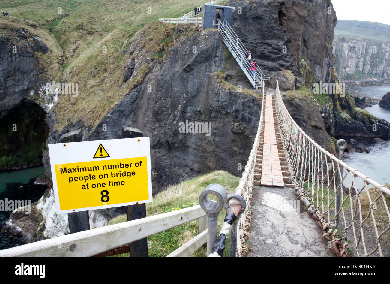 Segnale di avvertimento limitando il numero di persone che può attraversare il carrick a rede ponte di corde in una sola volta sulla contea di Antrim coast n Foto Stock