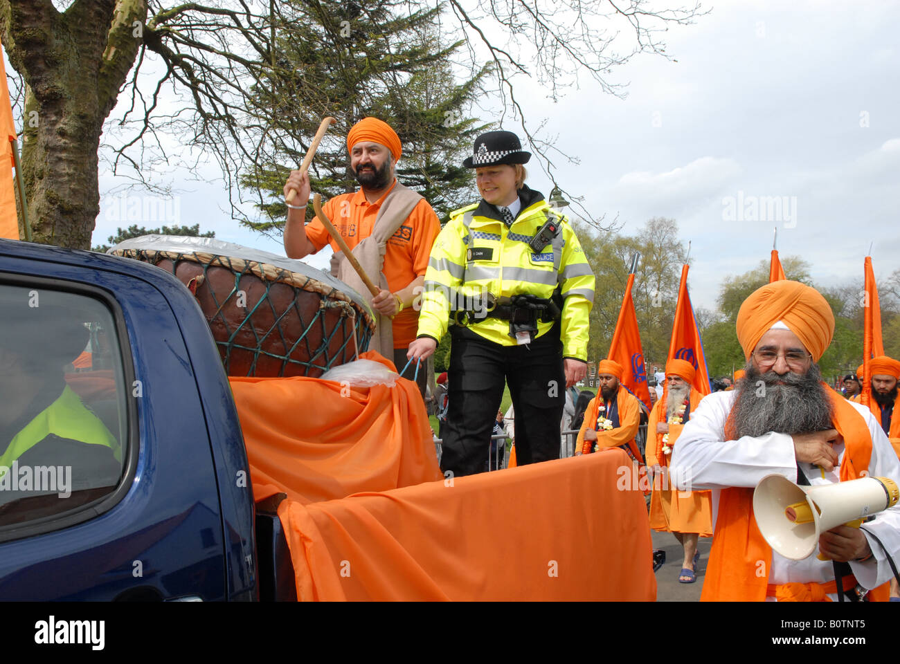Una parata di Vaisakhi batterista ottiene una mano da un funzionario di polizia a Birmingham Regno Unito Foto Stock