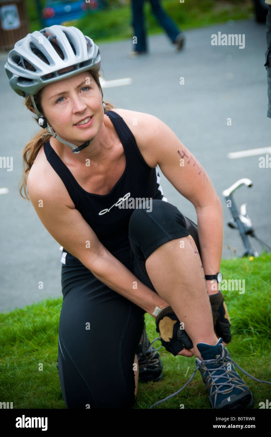 Giovane donna ciclista indossando il casco di sicurezza in Mountain Bike weekend di dimostrazione a Nant Yr Arian Forest park Ceredigion nel Galles Foto Stock