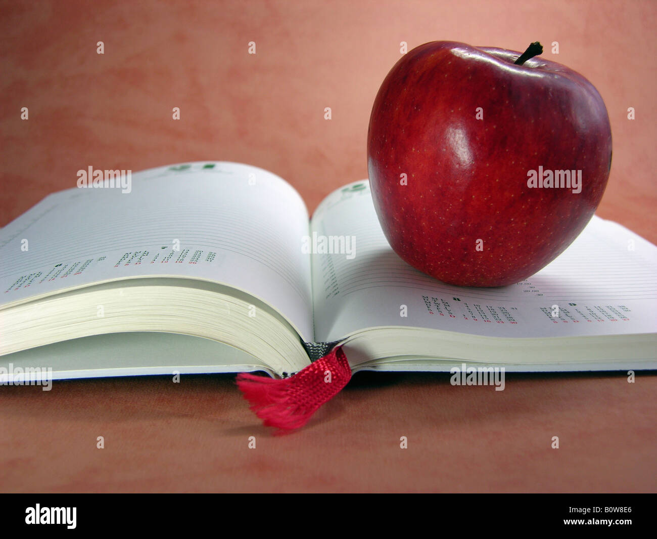 Red Apple su un libro aperto oppure giorno-planner con segnalibro rosso Foto Stock