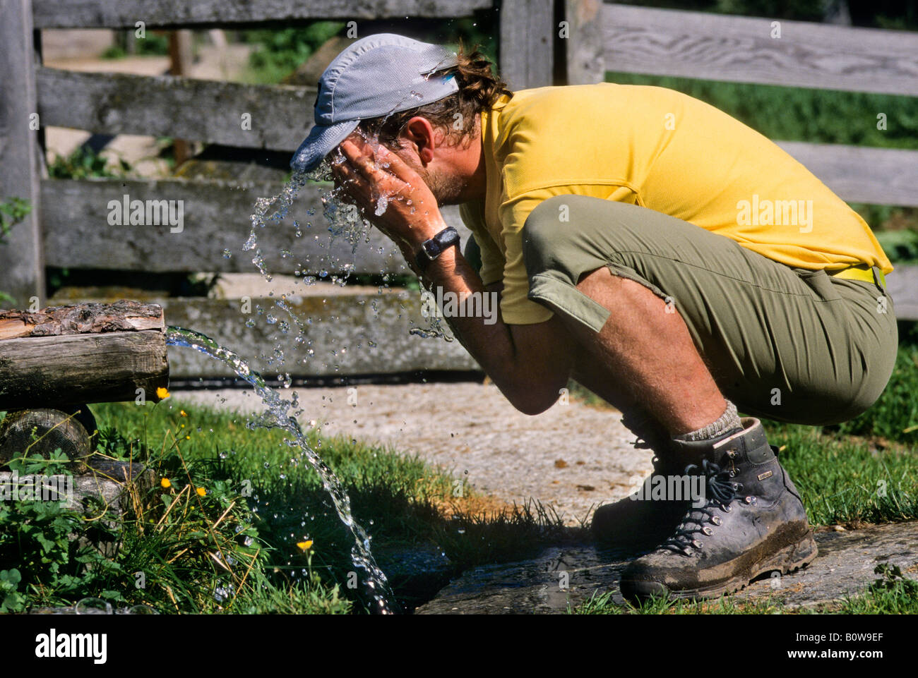 Escursionista rinfrescante se stesso in corrispondenza di una molla, Innergschloess, Hohe Tauern Range, Tirolo, Austria, Europa Foto Stock