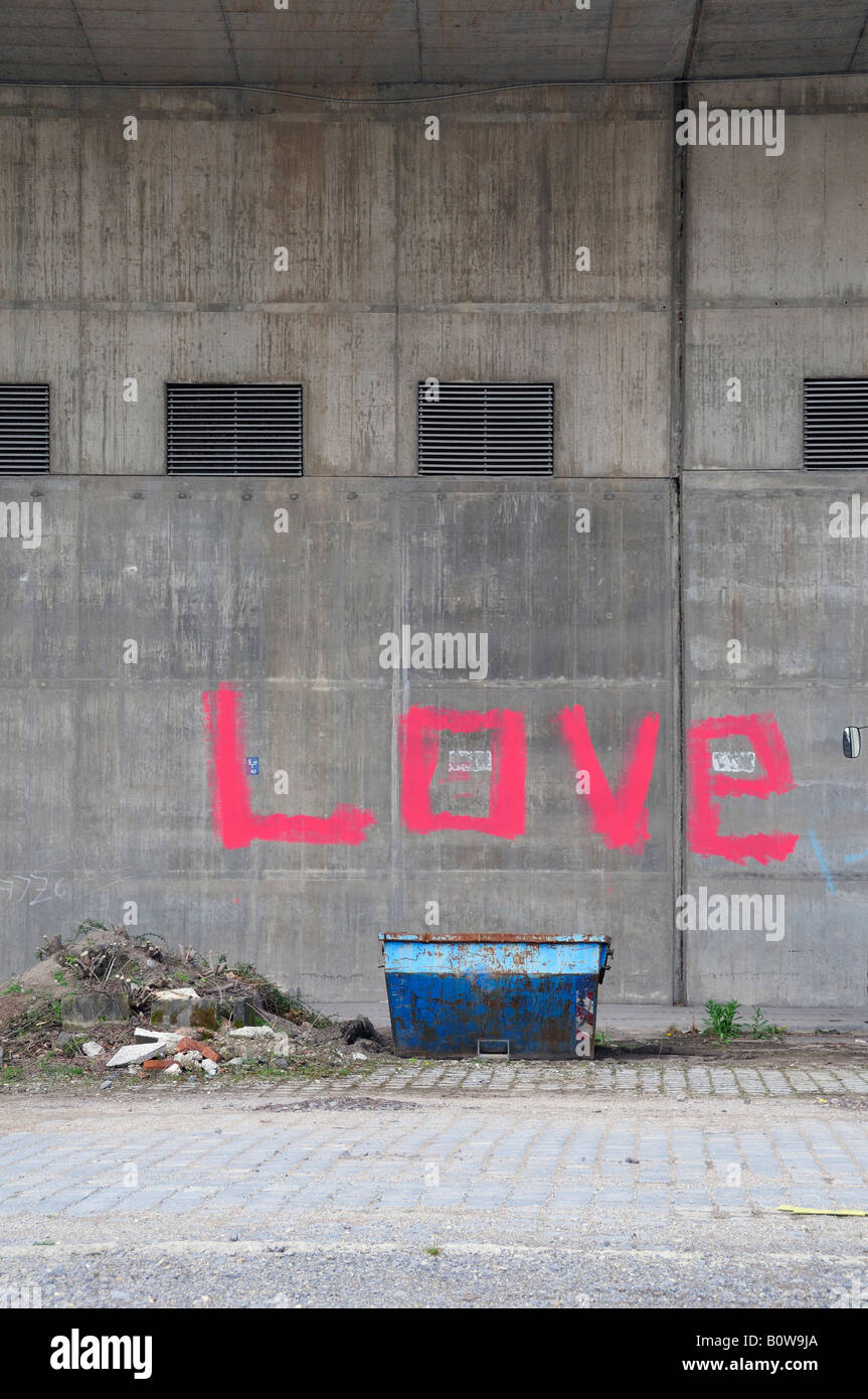 Contenitore di fronte a un muro con la parola amore spray-dipinta in rosa Foto Stock