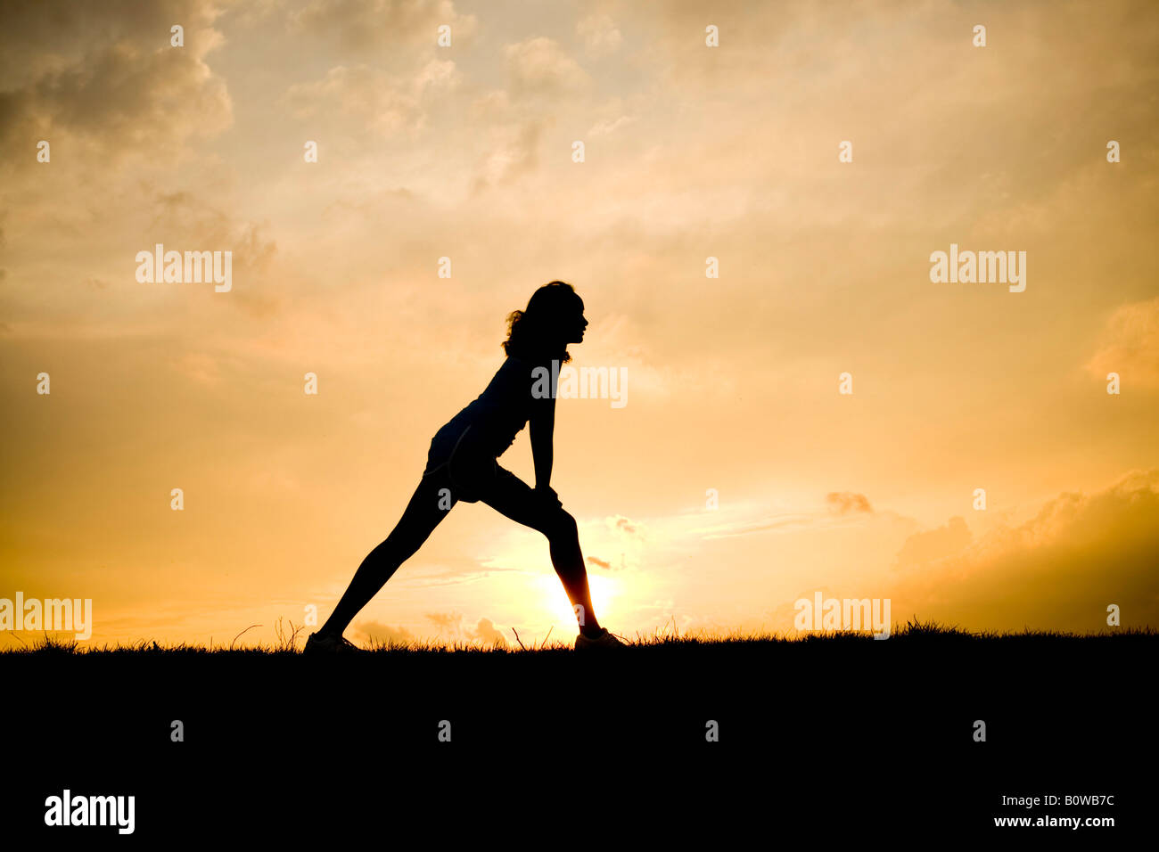 Silhouette di donna stretching al tramonto Foto Stock