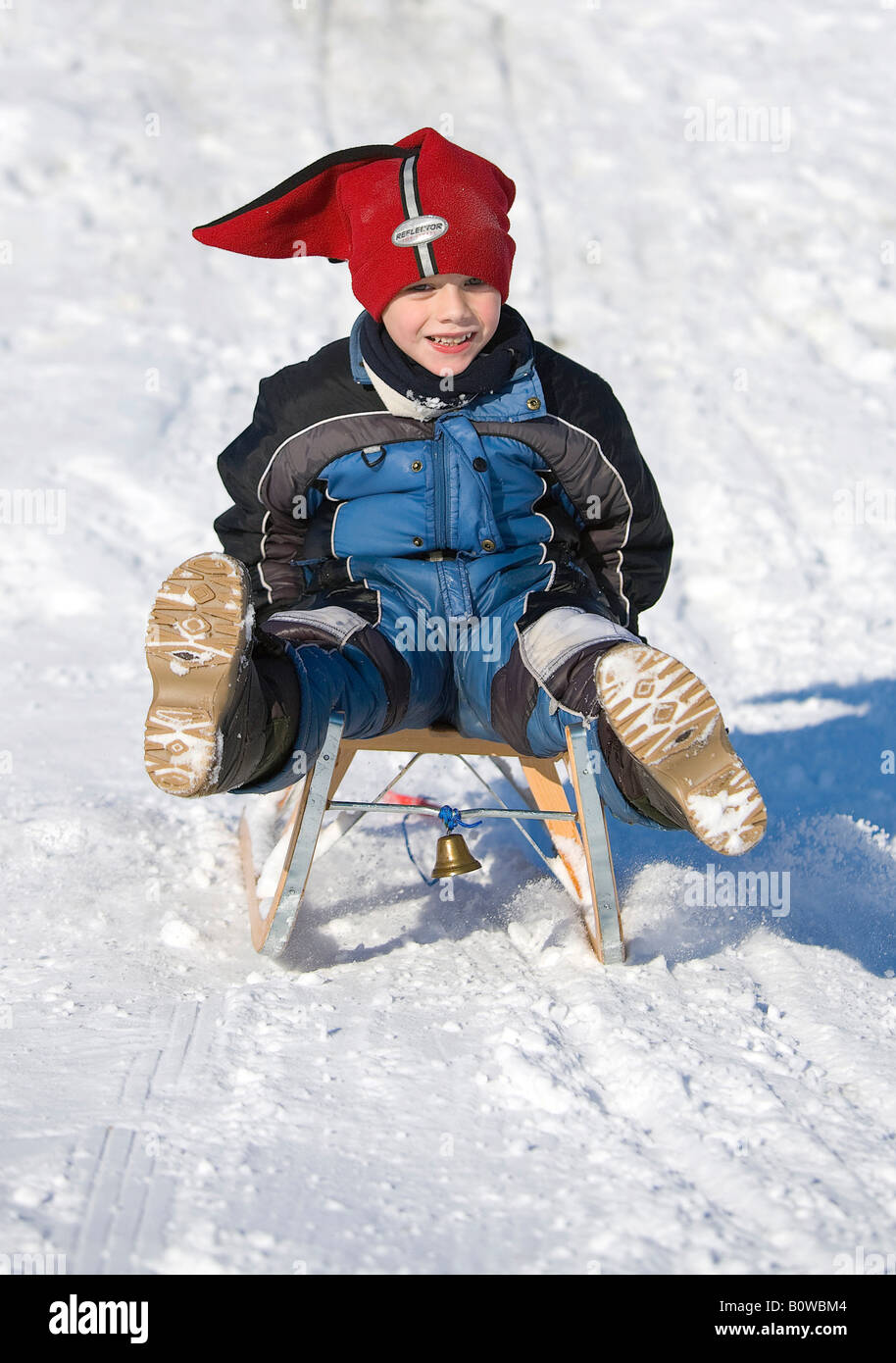 Cinque-anno-vecchio ragazzo cavalcare in discesa su una slitta, sled Foto Stock