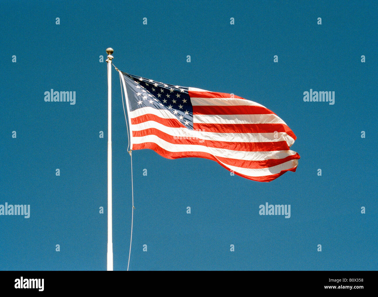 Una bandiera americana battenti contro un cielo blu chiaro Foto Stock