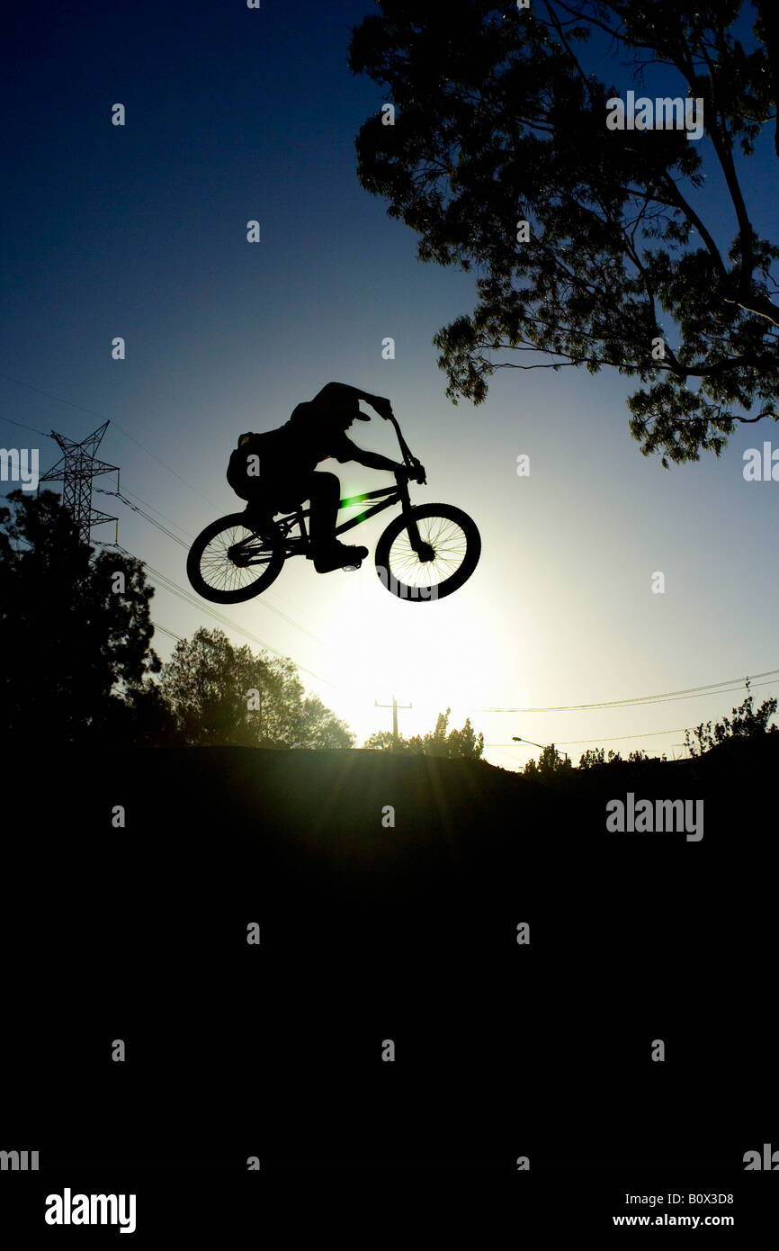 Silhouette di una persona che fa una stunt su una bicicletta BMX Foto Stock