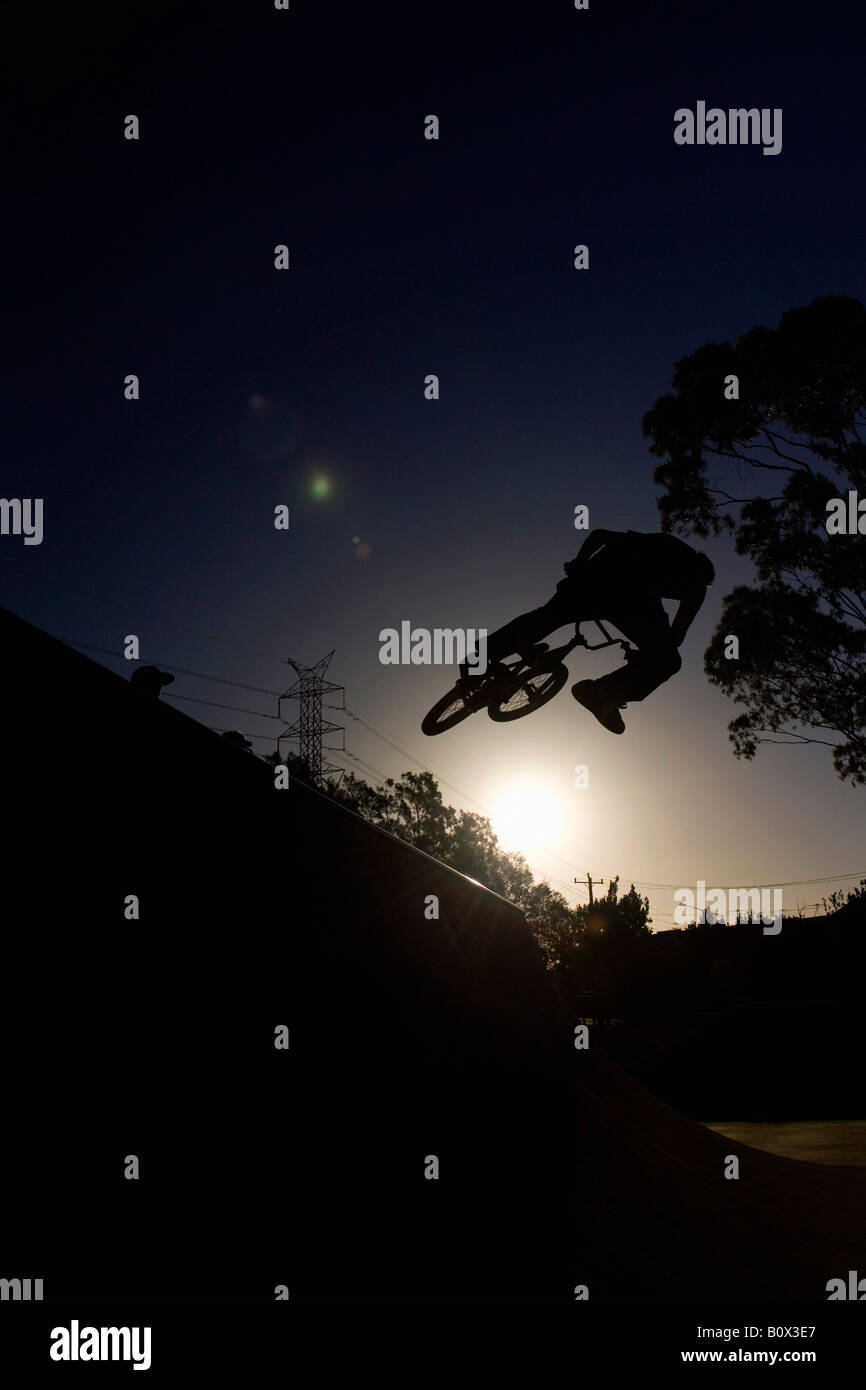 Silhouette di una persona che fa una stunt su una bicicletta BMX Foto Stock