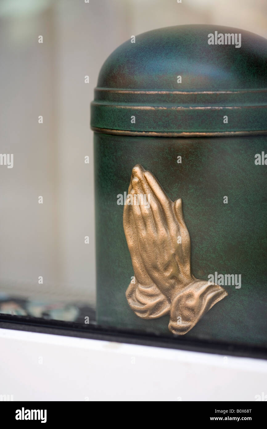 Una cremazione urna con la preghiera le mani su di esso Foto Stock