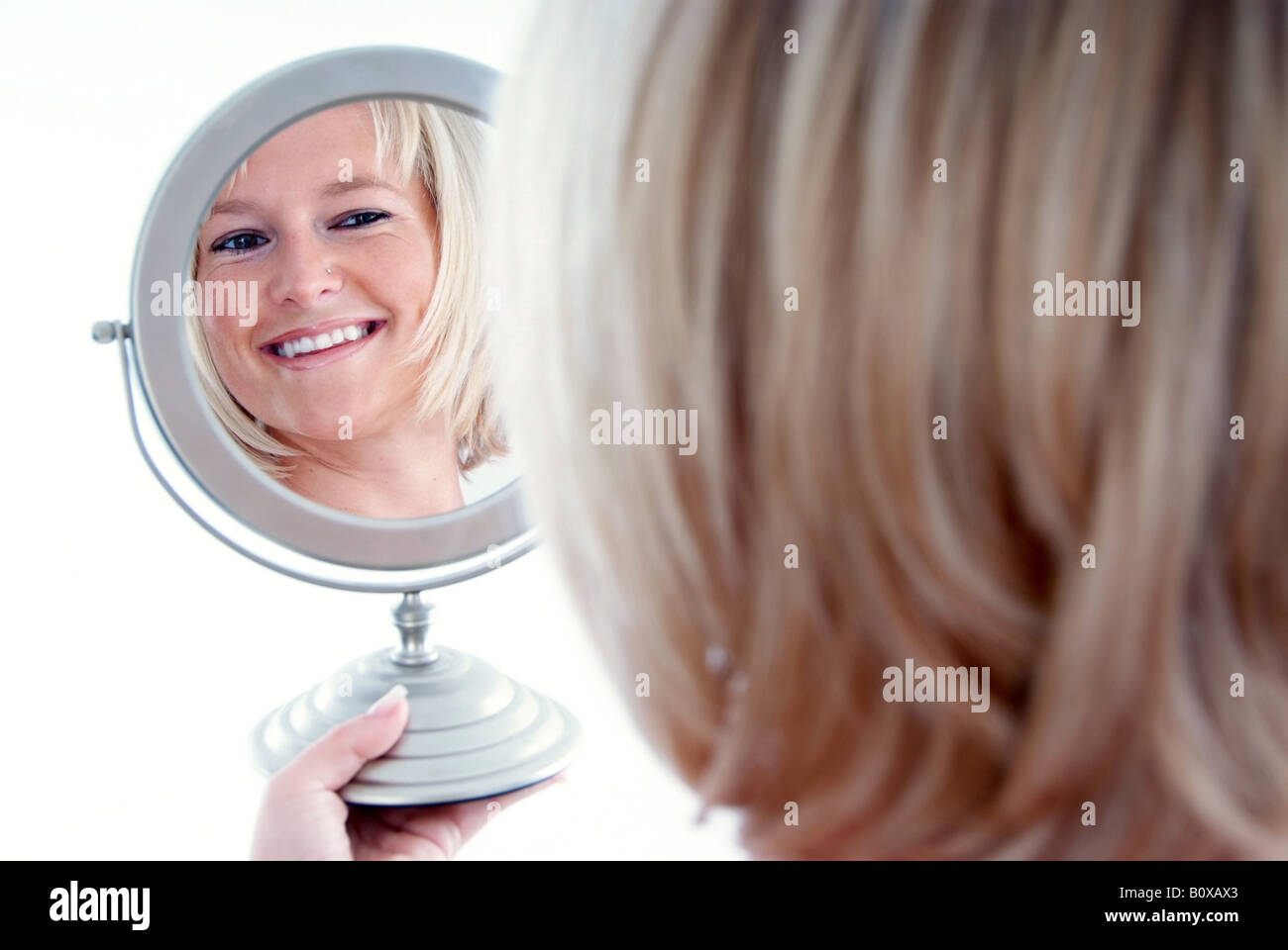 Donna bionda guarda nello specchio Foto Stock