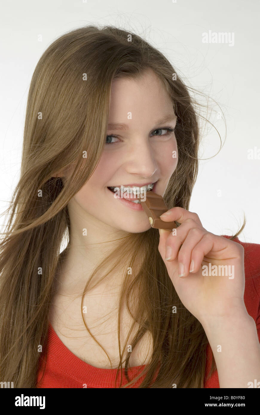 Brunette girl (13-14) mangiando cioccolato bar Foto Stock