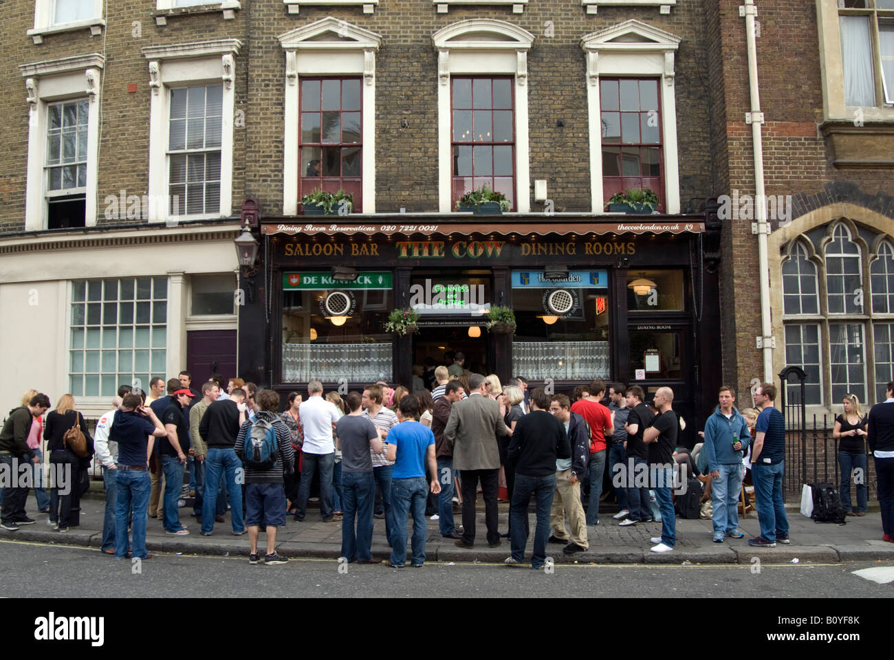 Persone di bere in strada al di fuori la vacca pub di Westbourne Park Road, Notting Hill, Londra Inghilterra REGNO UNITO Foto Stock